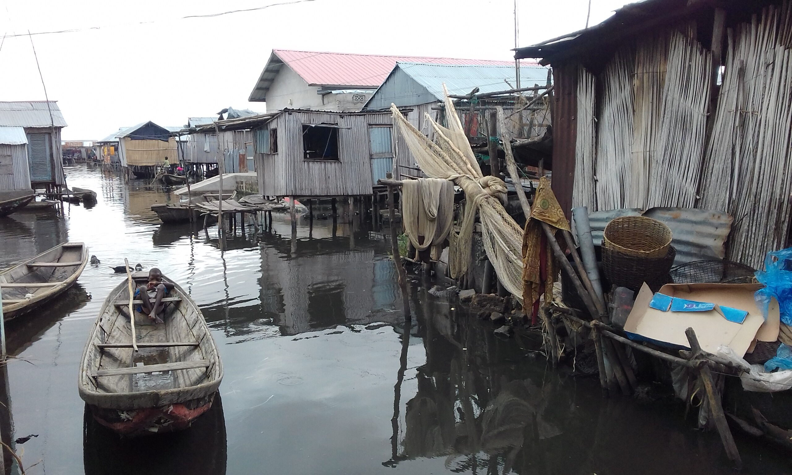 A street on Ladji, whith houses in piling over water, and a small boat in the center