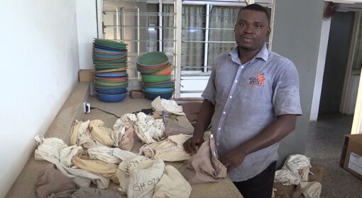 A scientist next to many bags of soil.