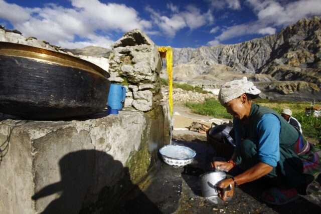 Women pumping water with the Himalayan mountains in the background, Nepal